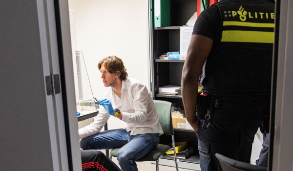 Forensisch arts Ricardo geeft medische zorg aan een arrestant onder toeziend oog van een politie agent